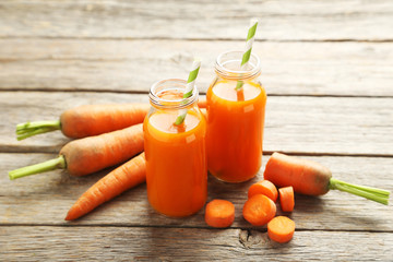 Fresh carrot juice in bottles on a grey wooden table