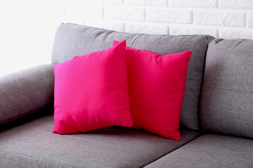 Colorful pillows on grey sofa on a brick wall background