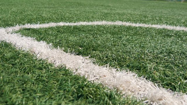Close up of the out of bounds line on a turf football field. Green grass