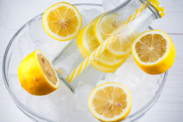 Lemonade drink in trendy bottle with straw on ice.