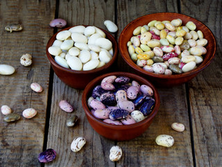 Fototapeta na wymiar young beans of different varieties and colors in a clay bowl on a wooden background. selective focus