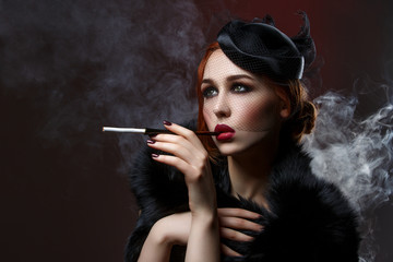 Beautiful girl with smoky eyes and red lips holding cigarette