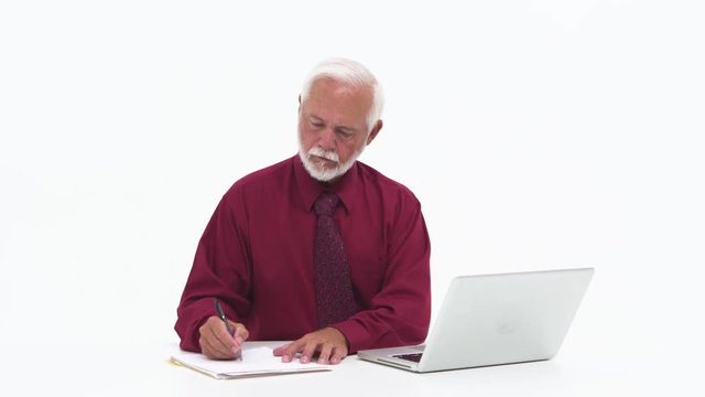 Senior elderly man taking notes and using laptop