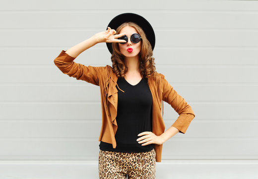 Fashion pretty woman wearing a black hat, sunglasses and jacket