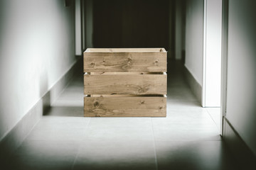 Empty wooden container box in the middle of an indoor dark home corridor