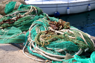 Old ropes and fishing nets and rusty anchors on the shore. Selective focus.