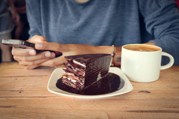 woman use mobile phone with coffee cup and chocolate cake.