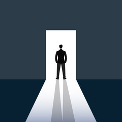 Man in suit standing in opened door towards light