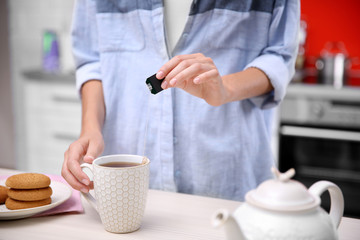 Woman with cup of tea in kitchen