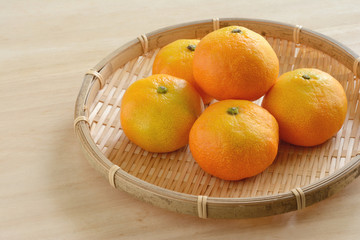 ザルに入ったミカン　木目背景　　
