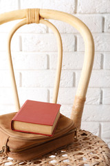 Fototapeta na wymiar Book with handbag on wicket chair