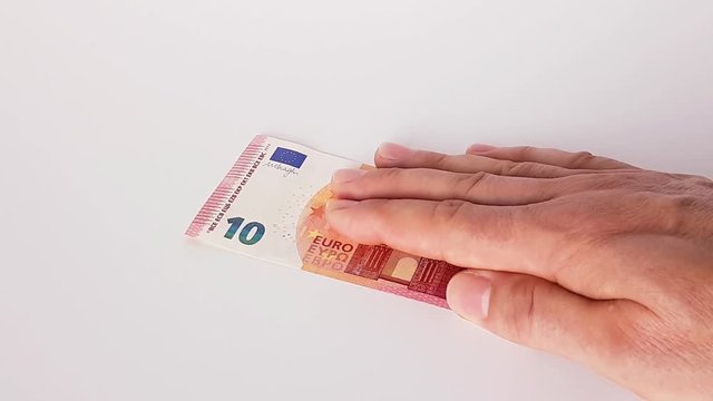 10 Euro werden von einer m&auml;nnlichen Hand auf einen Tisch geschoben
