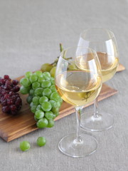 Glasses of wine with grapes on wooden board