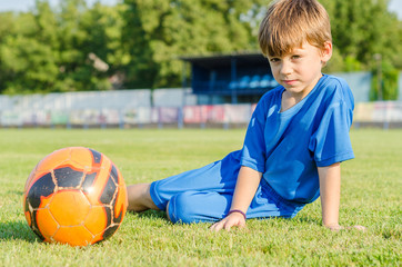 Child posing on the grass in a football dress, footballer siitin