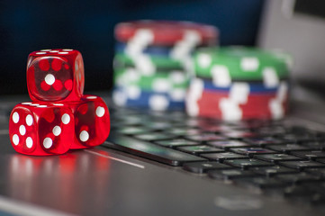 Gambling chips and red dice on laptop keyboard background