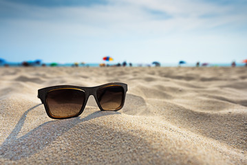 Sun glasses lie on a beach near the sea.