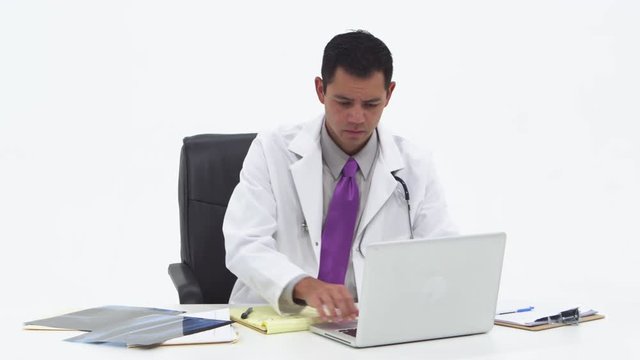 Young doctor checking x-rays and using laptop