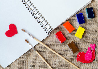 The paper hearts and notebook with brushes on the sackcloth