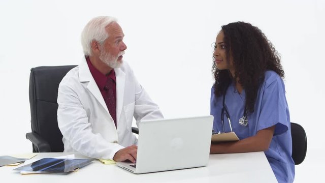 Senior doctor using laptop with nurse