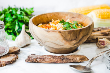 red lentil soup with corn, paprika and herbs in wooden plate