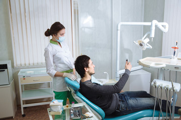 Dentist man with his patient doing photo selfie in dental office. Concept of healthy