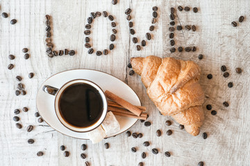 Cup of coffee with grains, croissant, turkish delight and cinnamon sticks on wooden background. title i love coffee.