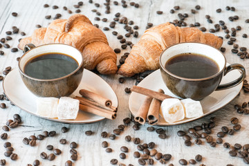 Cup of coffee with grains, croissant, turkish delight and cinnamon sticks on wooden background