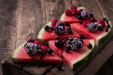 colorful tropical fruit watermelon pizza topped with berries cut into segments