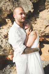 Young models couple posing on the beach with stones