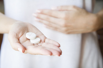 Woman is holding a lot of different pills in her  hands