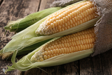 Fresh corn on cobs on rustic wooden table, closeup
