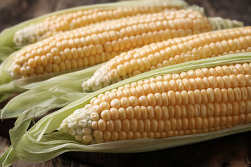 Fresh corn on cobs on rustic wooden table, closeup