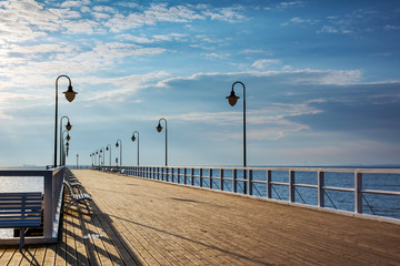 Wooden pier with benches and lanterns in the morning. Gdynia-Orlowo. Poland.