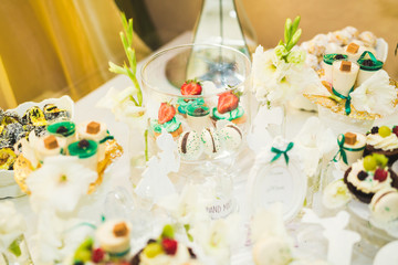 Delicious and tasty dessert table with cupcakes shots at reception closeup
