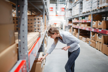 Serious staff woman wrting on notepad at supermarket