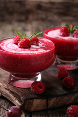 Pink raspberry smoothie with ice cream and mint on a rustic wood background