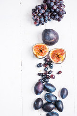 Ripe Grapes, plums and Figs on white wooden table