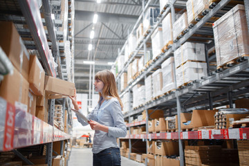 Serious staff woman wrting on notepad at supermarket