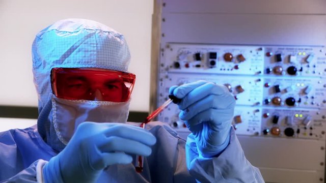 A CDC or biohazard lab tech in a laboratory looking at a blood sample.