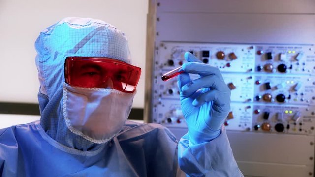 A CDC or biohazard lab tech in a laboratory looking at a blood sample.