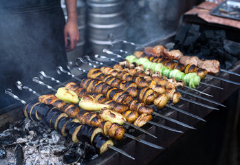 Grilled vegetables barbecue skewers vegetarian picnic food shish kebab with roasted pepper, potatoes, champignon, eggplant, zucchini on coal ember brazier. Concept of lifestyle street food preparation