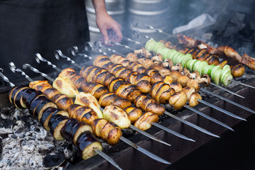 Grilled vegetables barbecue skewers vegetarian dinner picnic food shish kebab with roasted pepper, potatoes, champignon, on coal ember brazier. Concept of lifestyle rustic street food preparation