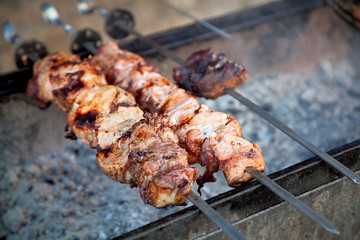 Preparation of barbecue meat shish kebab on skewers grill. Concept of lifestyle street food. Grilling traditional party picnic marinated pork beef and lamb on coal ember brazier.
