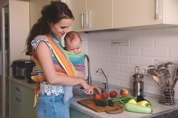 Young mom cooking in the kitchen with the baby. Vegetarian healthy food. Healthy food breastfeeding mothers. - obrazy, fototapety, plakaty