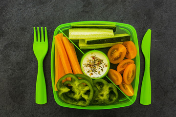 Tasty vegetarian food in plastic lunch box on dark background.