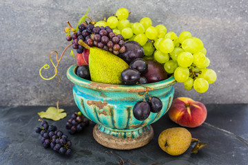 Beautiful still life with grapes and figs and other fruits on stone background.
