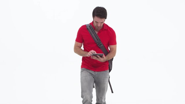 Young caucasian using tablet and walking