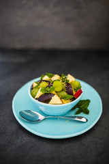 Healthy and delicious fruit salad with granola on stone background.
