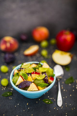 Healthy and delicious fruit salad with granola on stone background.