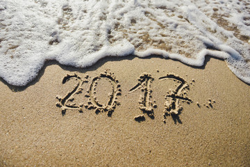 2017, message written in the sand at the beach background
